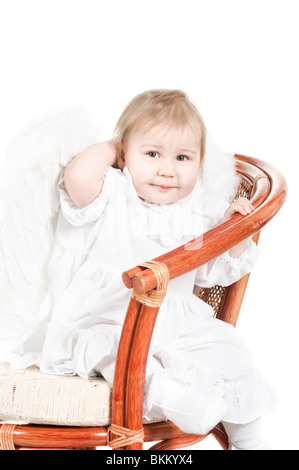 Bambino seduto sulla sedia. Studio shot. Isolato su sfondo bianco. In le ali di angelo Foto Stock