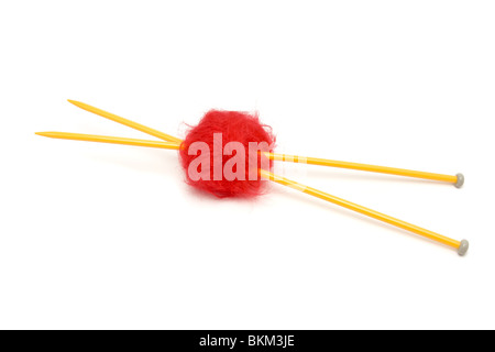 Una piccola palla di rosso la lana mohair trafitto con grande giallo aghi da maglia contro il bianco. Foto Stock