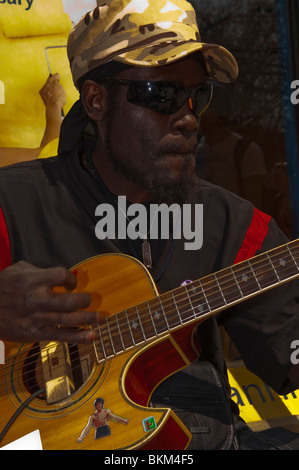 Un modello rilasciato suonatore ambulante maschio chiamato Juggernaut 1a suonare la chitarra nelle strade di Norwich , Inghilterra , Regno Unito Foto Stock