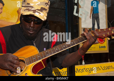 Un modello rilasciato suonatore ambulante maschio chiamato Juggernaut 1a suonare la chitarra nelle strade di Norwich , Inghilterra , Regno Unito Foto Stock