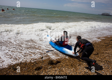 Istruttore dal Brighton Seafront kayak, l'operatore spinge un principiante in modo mare. Foto Stock