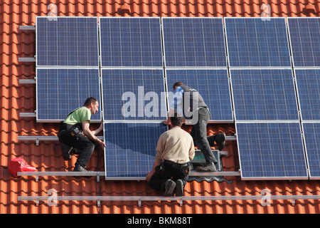 Operai di installare pannelli solari sul tetto Foto Stock