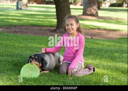 Giovane africano ragazza americana pone con un cane e il suo frisbee Foto Stock