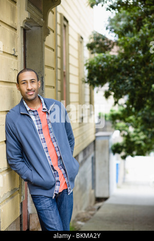 African American uomo appoggiato a lato dell'edificio Foto Stock