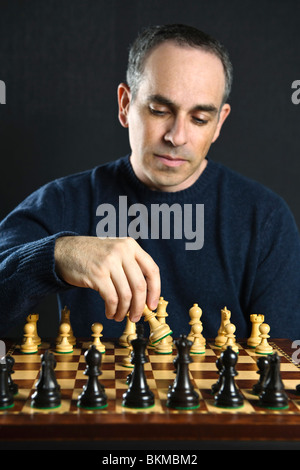 L uomo lo spostamento di un pezzo degli scacchi sulla scacchiera in legno Foto Stock