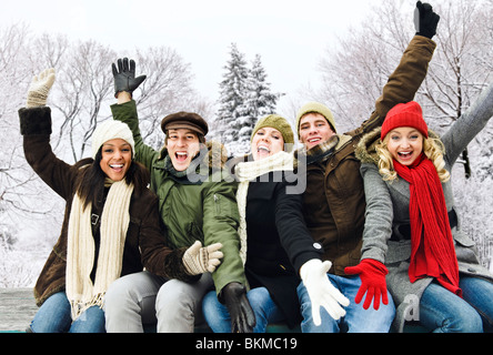 Gruppo di entusiasti giovani amici con le braccia sollevate all'aperto in inverno Foto Stock