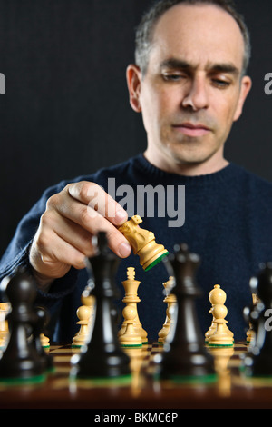 L uomo lo spostamento di un pezzo degli scacchi sulla scacchiera in legno Foto Stock