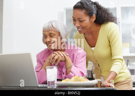 African American donna aiutando la madre con il computer portatile Foto Stock
