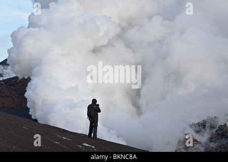 Tourist fotografando le nuvole di vapore in cui i flussi di lava incontrare neve e ghiaccio dal ghiacciaio Eyjafjallajökull in Islanda Foto Stock