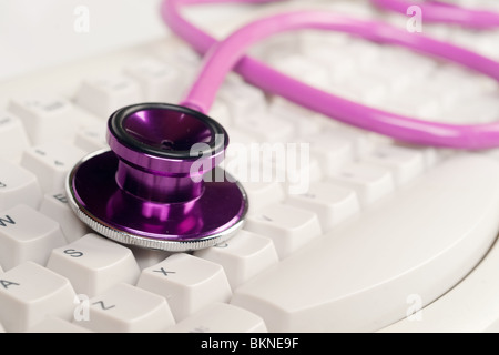 Immagine di un stetoscopio rosa su una tastiera bianca Foto Stock