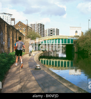 Pareggiatore e ciclista passando sul Regents Canal alzaia vicino a ponte verde Hoxton in Londra England Regno Unito Foto Stock