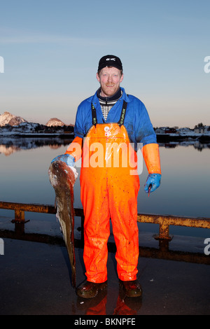 Un pescatore mantiene una sua linea di merluzzo pescato il pesce in Ballstad borgo peschereccio di Vestvågøy, una delle isole Lofoten in Norvegia Foto Stock