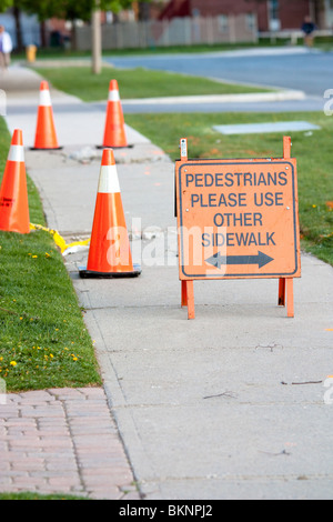 I pedoni si prega di utilizzare altro lato piedi segno arancione rotto road arancione coni cono pericolo concreto di erba passerella Foto Stock