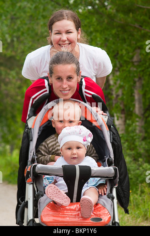 Due giovani donne adulte con carrozzina e due bambini piccoli in esso Foto Stock