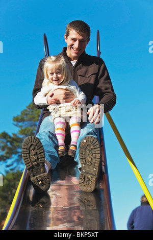 Un padre e figlia di andare giù a far scorrere insieme al parco giochi Foto Stock