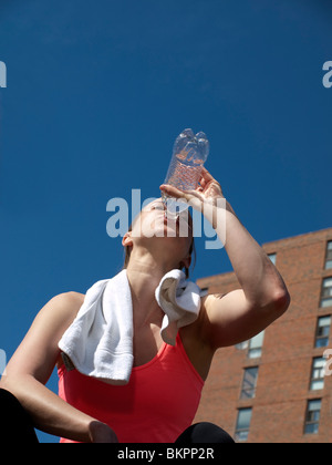 Giovane donna con asciugamano e acqua di raffreddamento dopo l'esecuzione Foto Stock