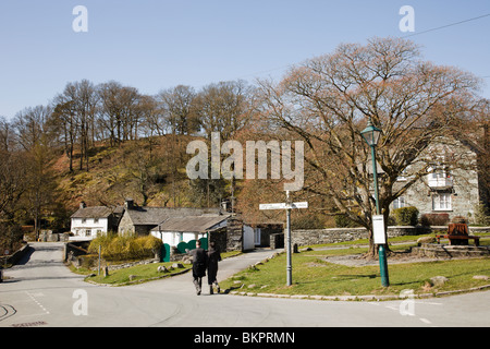 Due persone camminano attraverso il vecchio villaggio di lakeland nella Langdale Valley, nei laghi meridionali. Lake District National Park Elterwater Cumbria Inghilterra Gran Bretagna Foto Stock