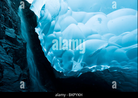 Una cascata di rivoli verso il basso la roccia di una caverna di ghiaccio all'interno dell'Mendenhall Glacier, Juneau, in Alaska Foto Stock