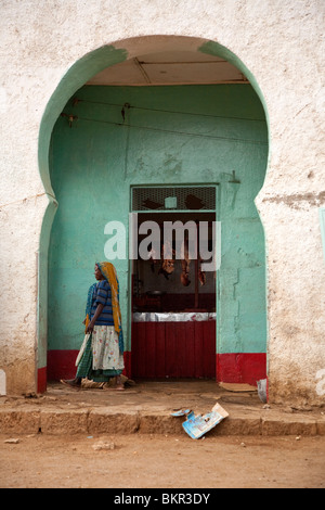 Etiopia, Harar. Una donna cammina passato un macellaio in Harar musulmana del mercato della carne. Foto Stock