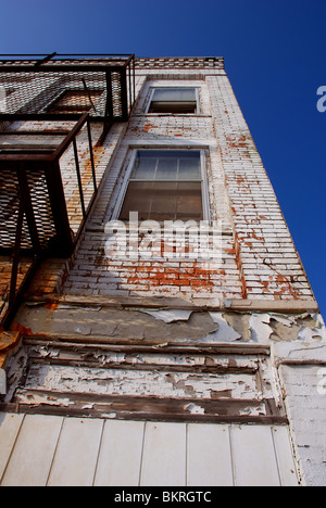 Vista verticale di un vecchio edificio abbandonato con arrugginita fire escape scalinata. Foto Stock