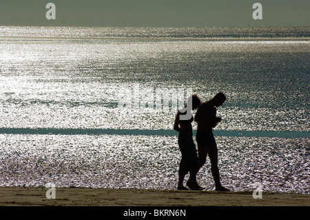 Coppia retroilluminato di camminare sulla spiaggia a Blackpool, Inghilterra Foto Stock