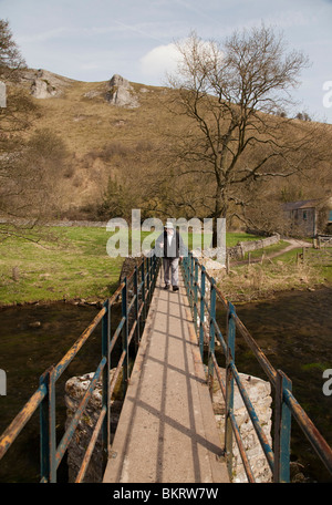 Uomo che cammina attraverso un ponte pedonale in Monsal Dale Derbyshire Peak District Inghilterra REGNO UNITO Foto Stock