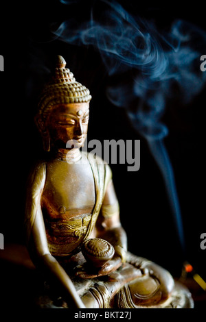 Budda statuetta con bastoncini di incenso Foto Stock