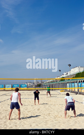 Persone a giocare a beach volley sulla sabbia di mare sul lungomare di Brighton nel tempo caldo e cielo blu Foto Stock