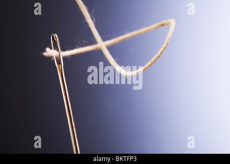 Filo bianco passando attraverso gli occhi di ago, primo piano Foto Stock