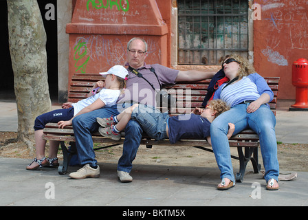 Whole family asleep on a park bench in Venice, Italy Foto Stock