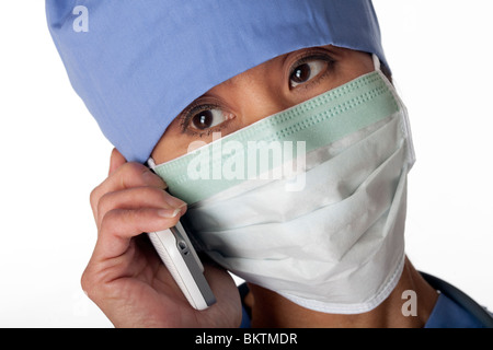 Primo piano di una donna asiatica professionista medico indossando scrubs e una maschera durante la conversazione su un telefono cellulare. Inquadratura orizzontale. Foto Stock