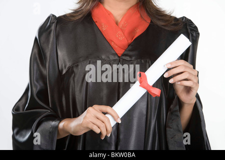 Giovane donna nel mondo accademico regalia holding scorrere, sezione mediana Foto Stock