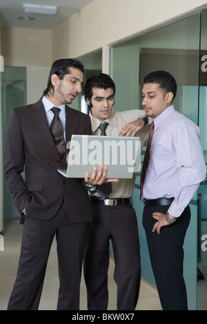 Uomo d affari con computer portatile avente la discussione con i colleghi in ufficio Foto Stock