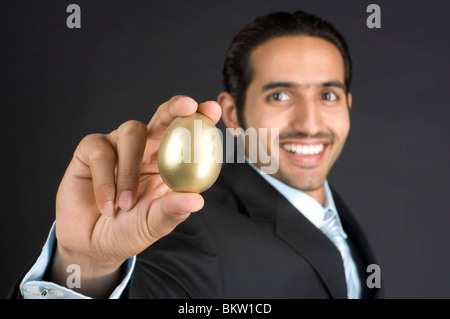 Imprenditore azienda Golden Egg, sorridente Foto Stock