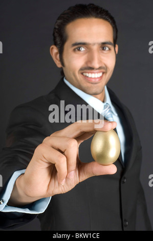 Imprenditore azienda Golden Egg, sorridente, ritratto Foto Stock