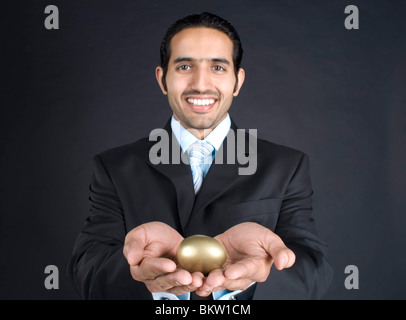 Imprenditore azienda Golden Egg, sorridente, ritratto Foto Stock