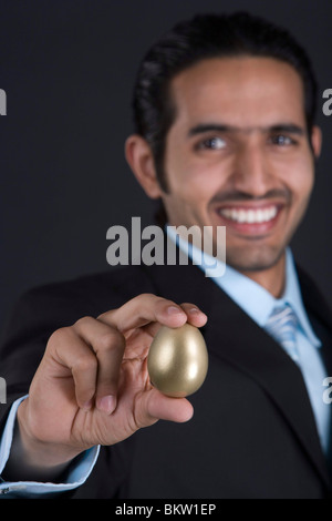 Imprenditore azienda Golden Egg, sorridente, ritratto Foto Stock