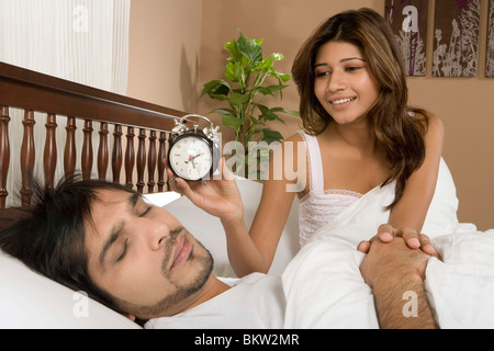 Moglie di svegliarvi marito con orologio Foto Stock