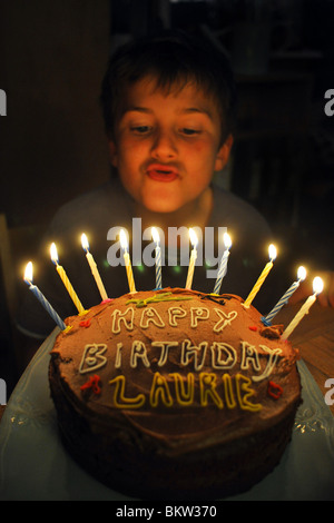 A dieci anni di vecchio ragazzo si brucia le candele sulla sua torta di compleanno Foto Stock