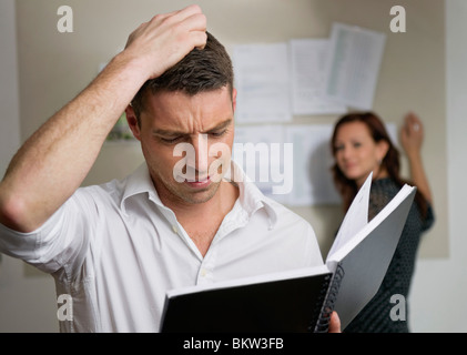 Uomo tormentato con i notebook in ufficio Foto Stock