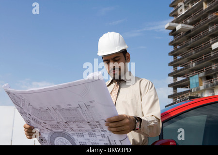 Architetto guardando blueprint al sito in costruzione Foto Stock