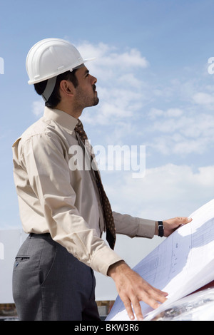 Giovane uomo con blueprint, ritratto Foto Stock