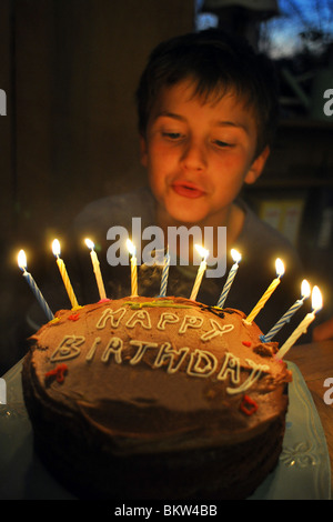 A dieci anni di vecchio ragazzo si brucia le candele sulla sua torta di compleanno Foto Stock