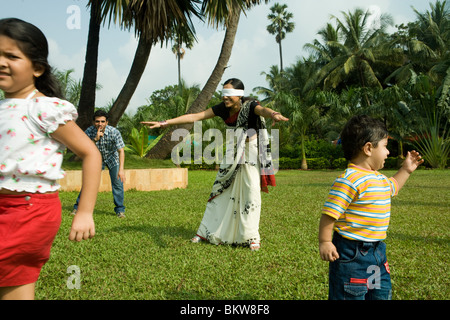 Famiglia giocando "cieco mans bluff' nel loro giardino Foto Stock