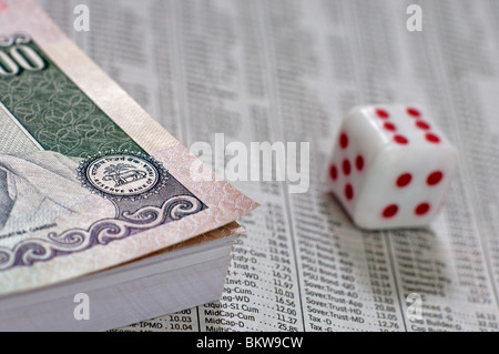 Bundle di rupia indiana di banconote con un dado sulla parte superiore della sezione business un giornale Foto Stock