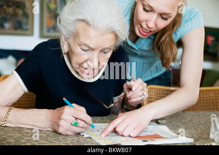 Due donne risoluzione cruciverba insieme Foto Stock