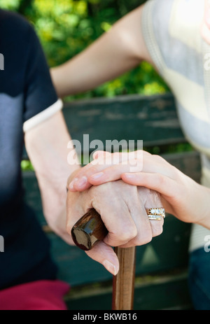 Mani appoggiate sul bastone da passeggio Foto Stock