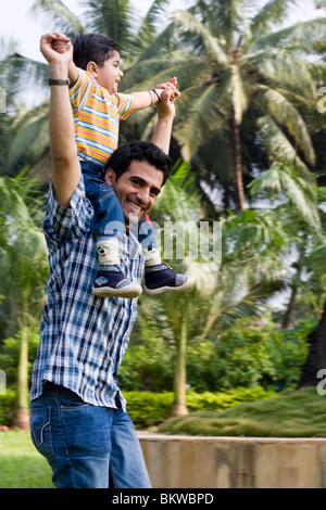 Un padre porta il suo figlio sulle spalle Foto Stock