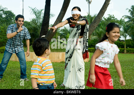 Famiglia giocando "cieco mans bluff' nel loro giardino Foto Stock