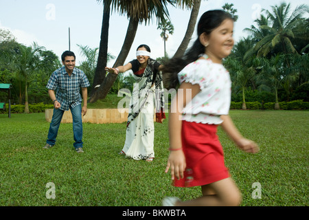 Famiglia giocando "cieco mans bluff' nel loro giardino Foto Stock